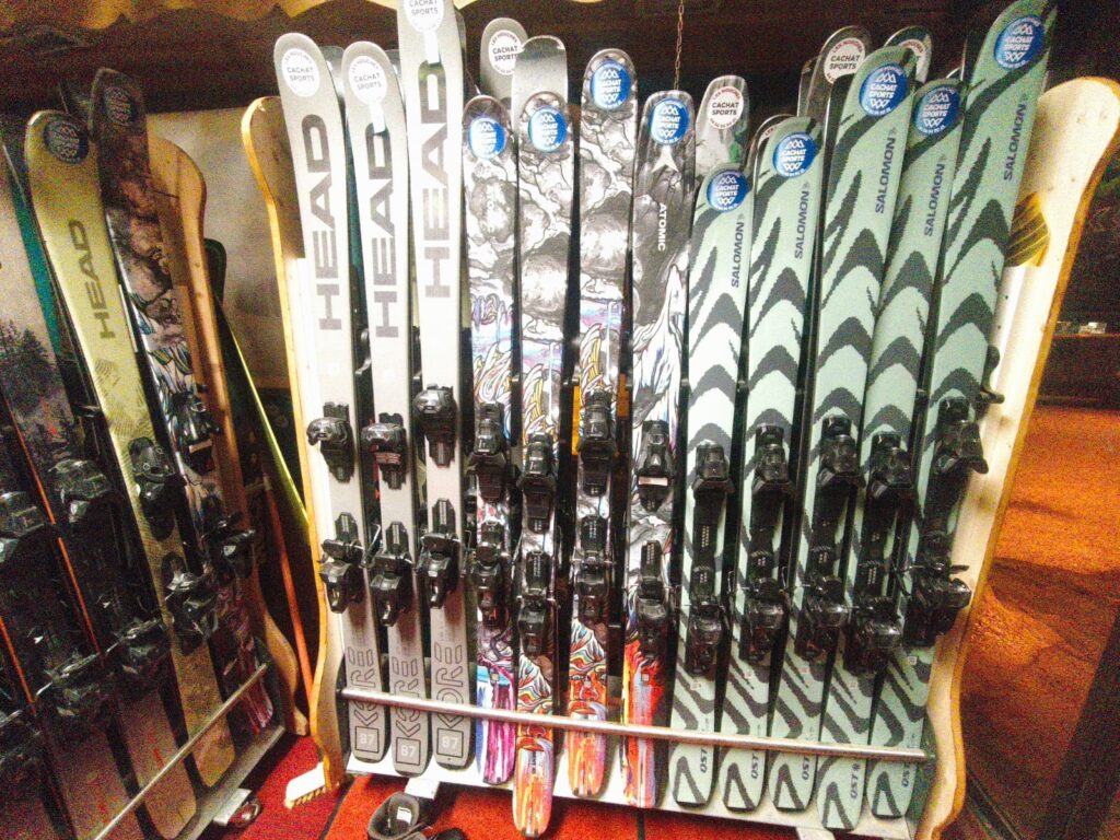 Skis HEAD, ATOMIC, SALOMON en location au magasin. Présentoir de skis HEAD, ATOMIC et SALOMON de location (Cachat Sports) avec fixations montées. Modèles variés dont QST et 87.